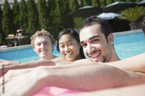 Portrait of four friends in the pool with an inflatable raft