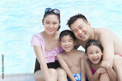 Family portrait, mother, father, daughter, and son, smiling by the pool 