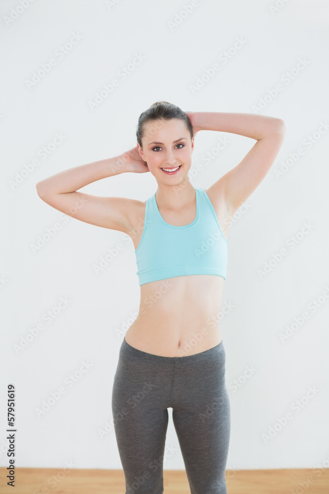 Smiling fit woman standing in fitness studio