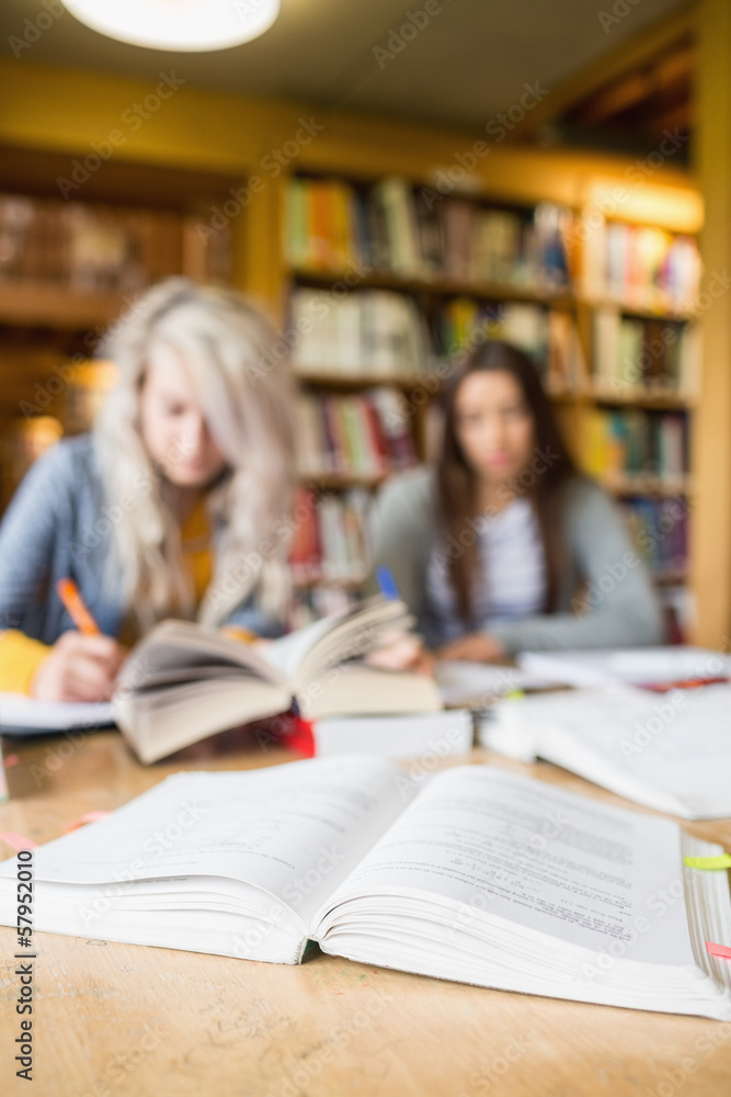 Two blurred students writing notes at library desk Two blurred students writing notes at library desk