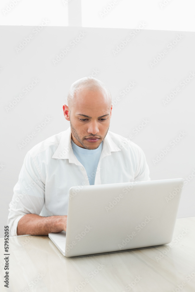 Casual serious young man using laptop at desk Casual serious young man using laptop at desk