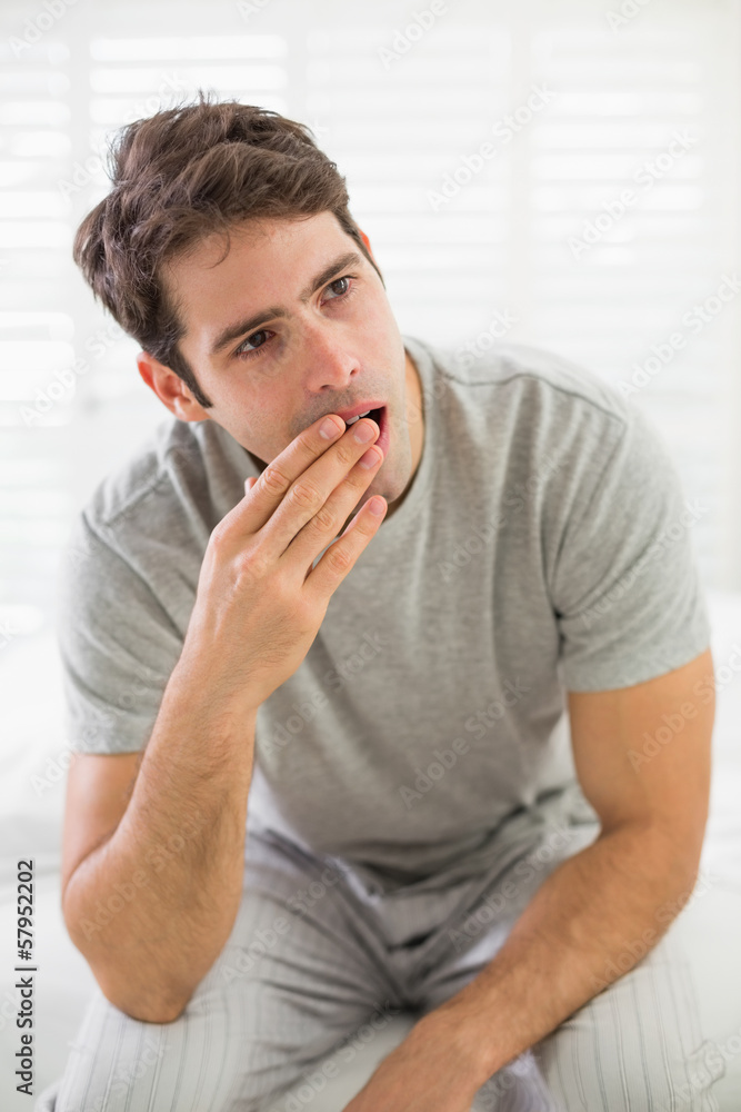 Sleepy young man yawning in bed Sleepy young man yawning in bed