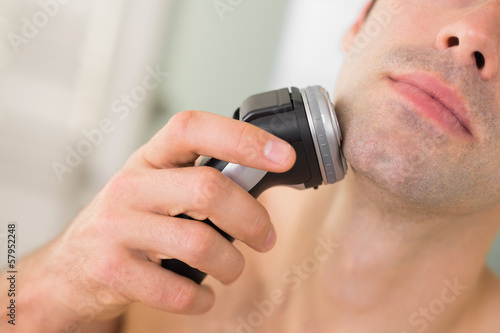 Extreme Close up of man shaving with electric razor photo