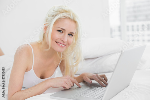 Portrait of a casual relaxed blond with laptop in bed