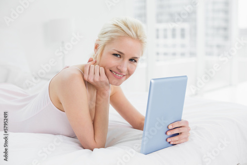 Free Download Smiling casual young blond with tablet PC in bed - GFXLoad