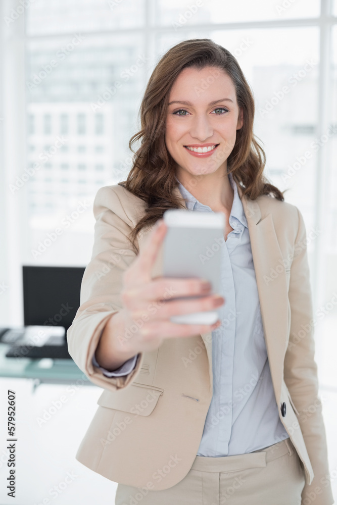 Smiling elegant businesswoman text messaging in office Smiling elegant businesswoman text messaging in office