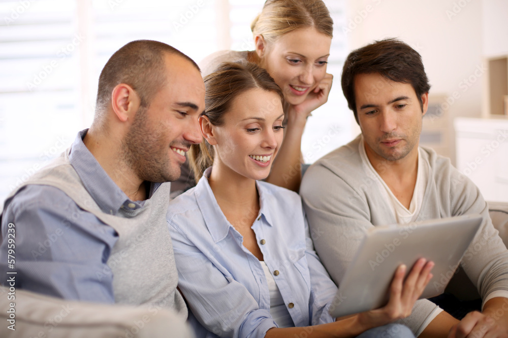 Group of friends at home using tablet in couch Group of friends at home using tablet in couch