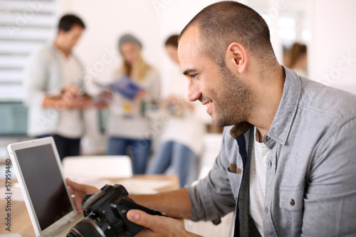 Cheerful reporter working in office on laptop