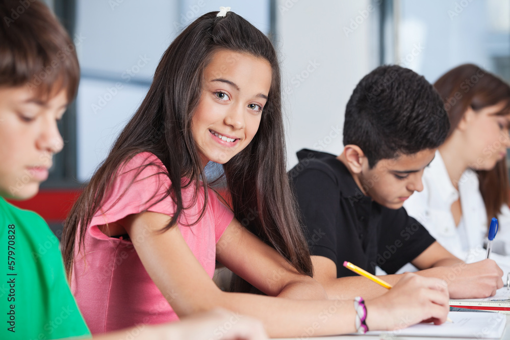 Teenage Girl Sitting With Classmates Studying At Desk