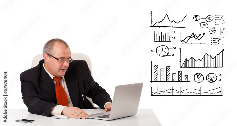 Businessman sitting at desk with diagrams and laptop Businessman sitting at desk with diagrams and laptop