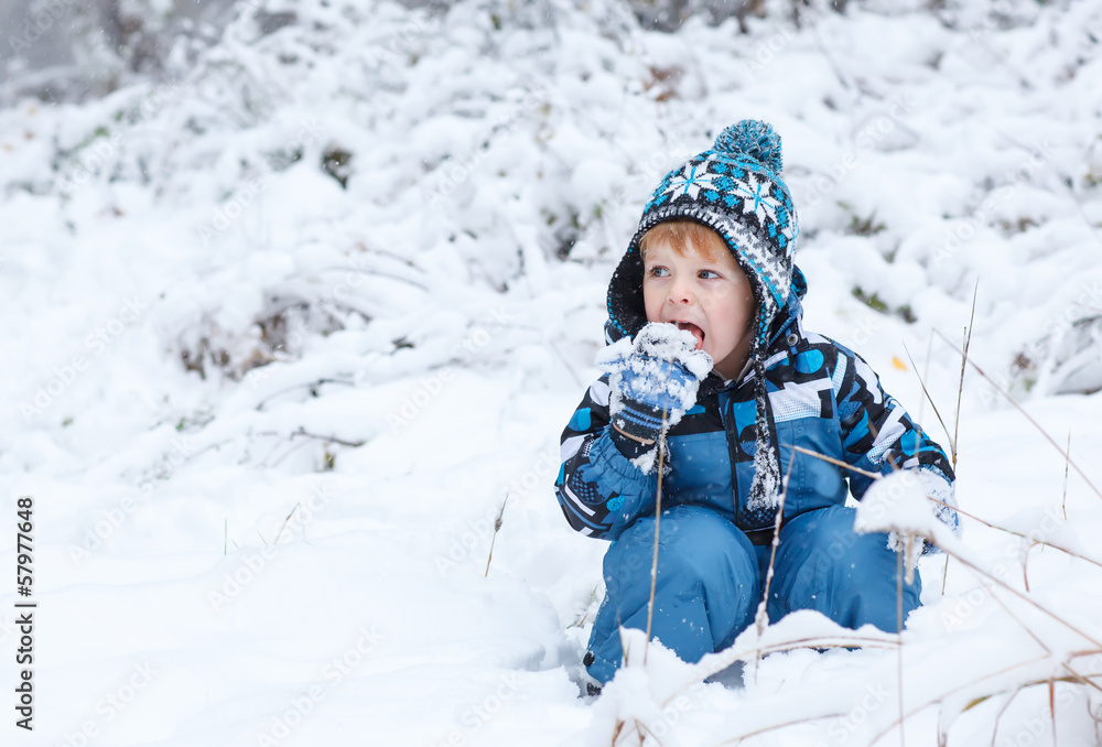 Adorable toddler boy having fun with snow on winter day Adorable toddler boy having fun with snow on winter day