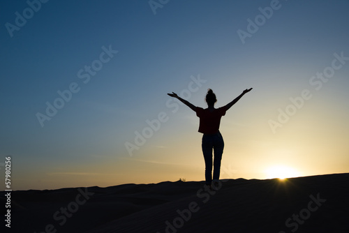 Silhouette de jeune femme bras levés à l'aube