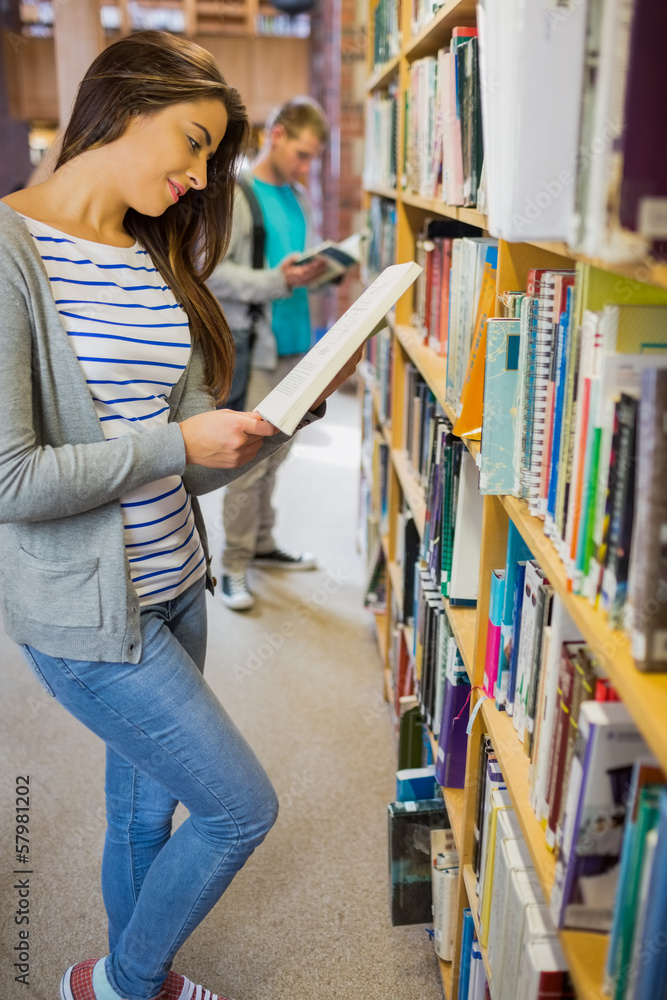 Students standing by bookshelf in the library Students standing by bookshelf in the library