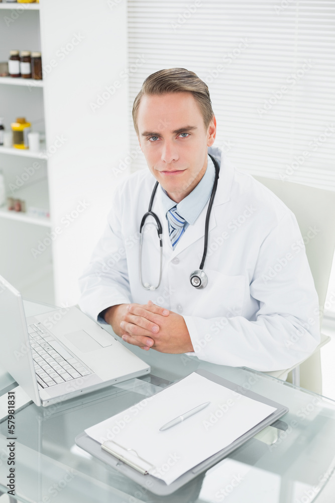 Serious male doctor with laptop at medical office Serious male doctor with laptop at medical office