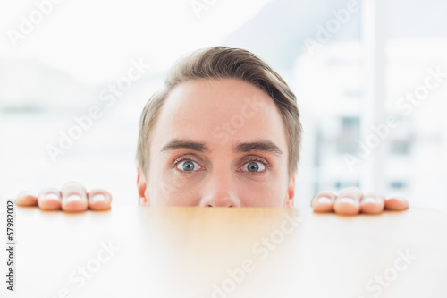 Portrait of businessman looking over blurred wall at office