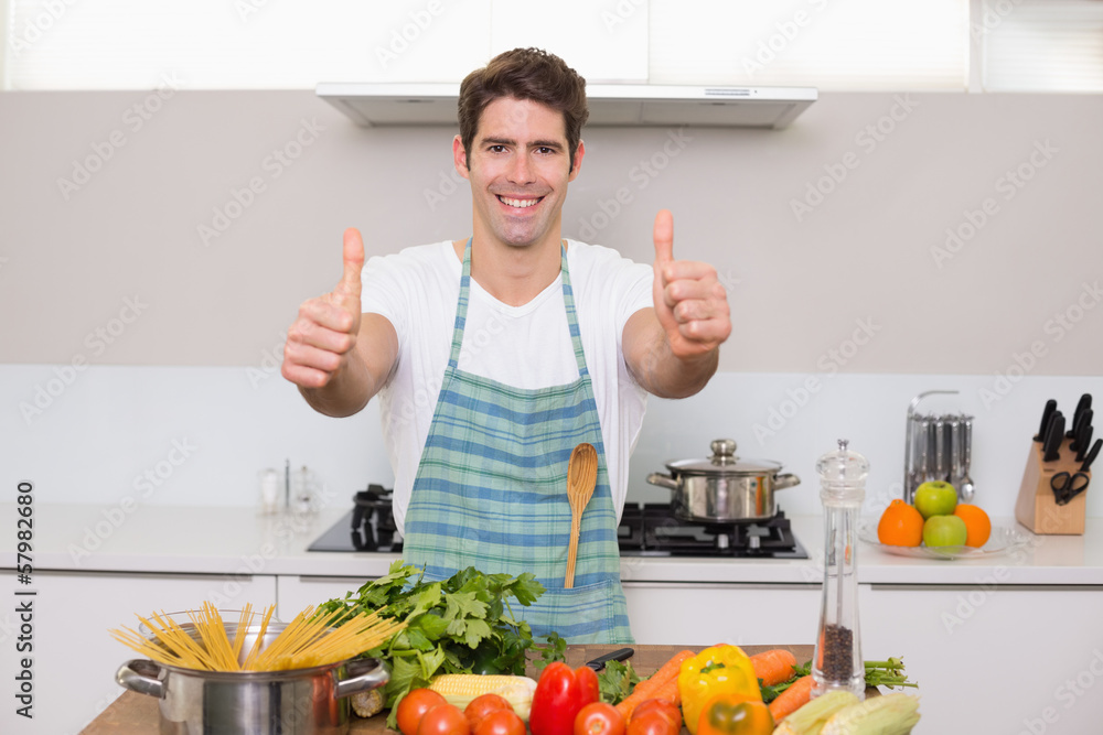 Smiling man with vegetables gesturing thumbs up in kitchen Smiling man with vegetables gesturing thumbs up in kitchen