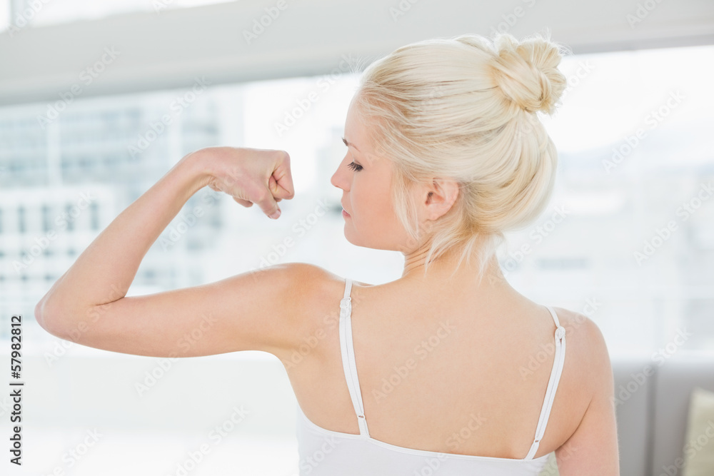 Rear view of fit woman flexing muscles in fitness studio
