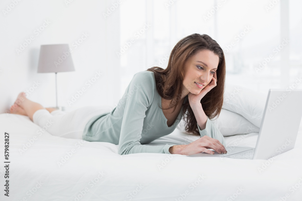 Relaxed casual woman using laptop in bed Relaxed casual woman using laptop in bed