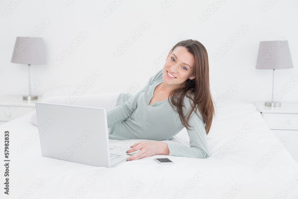 Relaxed casual young woman using laptop in bed Relaxed casual young woman using laptop in bed