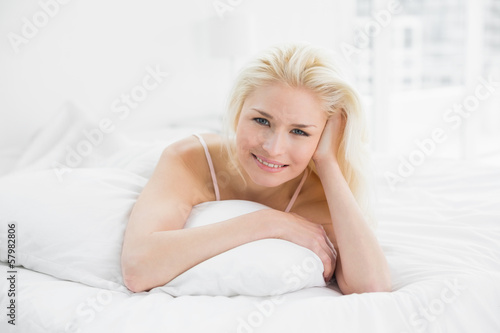 Smiling pretty young woman resting in bed