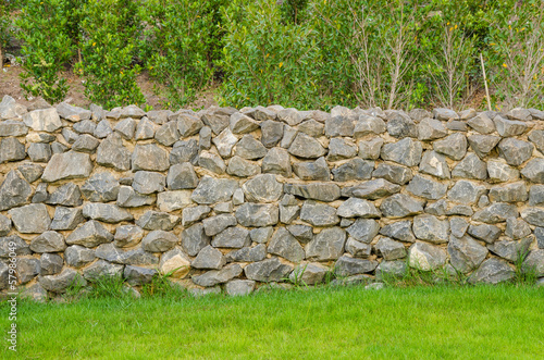 fence real stone wall surface with cement on green grass field photo