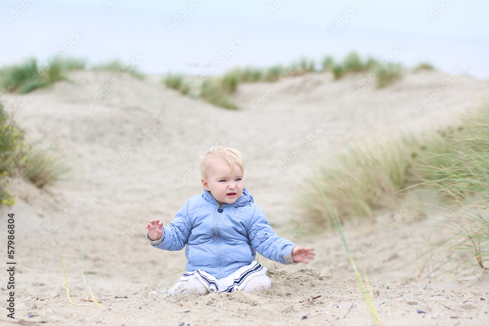 Happy blonde toddler girl plays in the dunes Happy blonde toddler girl plays in the dunes
