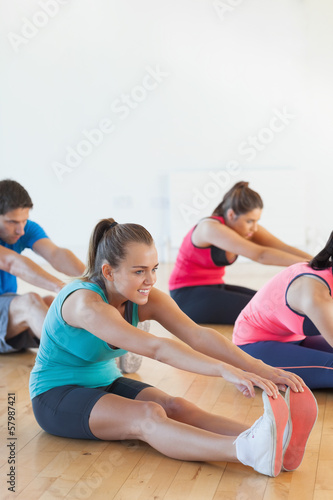 Class and instructor stretching legs in exercise room