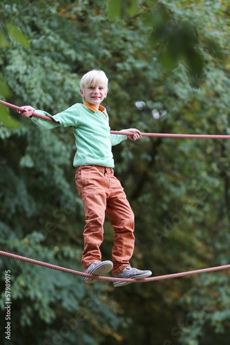 Happy teenager boy climbs on the ropes at playground 