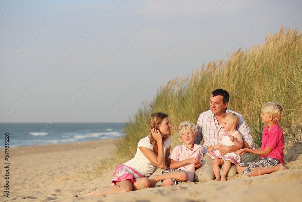 Family of five enjoys sunset at beach sitting together in dunes Family of five enjoys sunset at beach sitting together in dunes