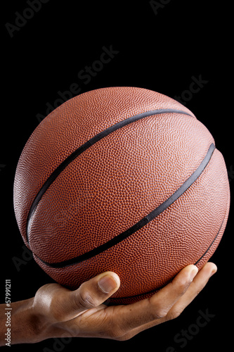Basketball player holding a ball against dark background © cristovao31
