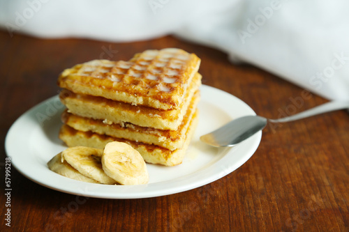 Sweet Belgium waffles with banana, on wooden table background