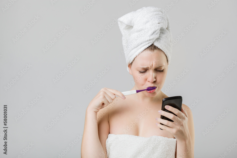 young girl watching her phone uncertainly while brushing her tee young girl watching her phone uncertainly while brushing her tee