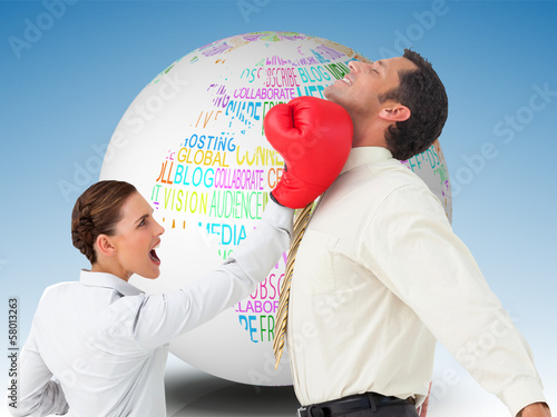 Composite image of businesswoman hitting a businessman with boxi photo