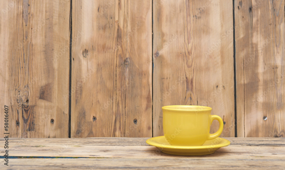 Yellow coffee cup and saucer on a wooden table Yellow coffee cup and saucer on a wooden table