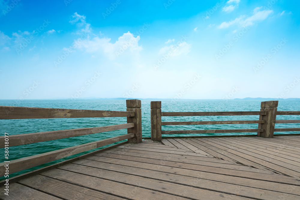 Wooden jetty over the beautiful Maldivian sea with blue sky