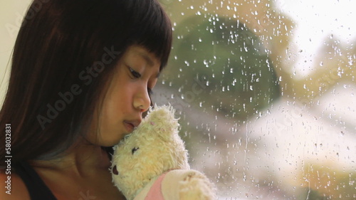 Sad Asian Girl Kisses Teddy Bear By Window