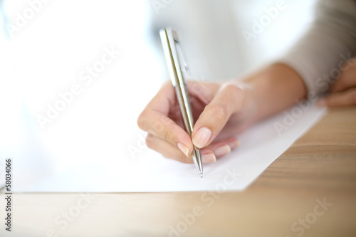 Closeup of woman's hand writing on paper