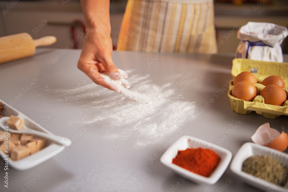 Motion blurred closeup on housewife sprinkling flour on table