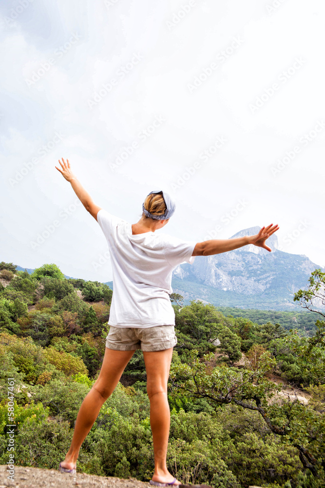 Young happy woman standing on a rock Young happy woman standing on a rock