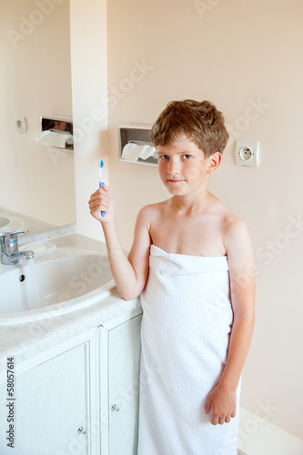 Boy holds dental cleaning brush against sink