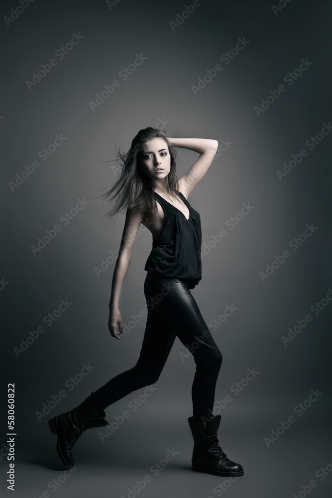 Fashion model wearing leather pants posing on grey