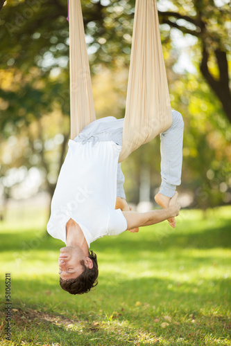 Aerial yoga, man doing yoga exercises in the park