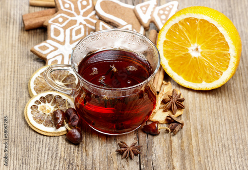 Glass of hot steaming tea among christmas decorations on wooden