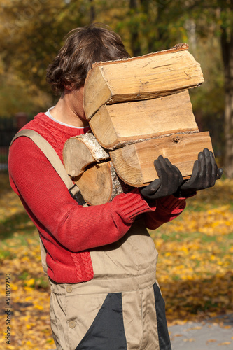 Young worker holding a stack of firewood photo