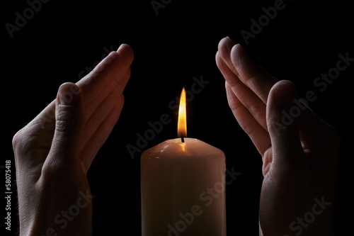adult male hands protect burning candle