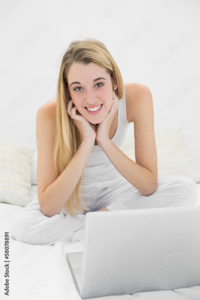Content blonde woman smiling at camera while using her notebook Content blonde woman smiling at camera while using her notebook