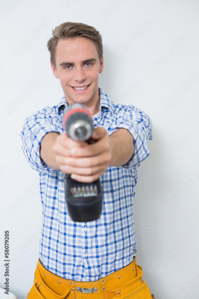 Smiling handsome young handyman holding drill Smiling handsome young handyman holding drill