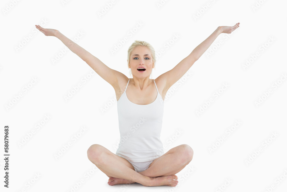 Toned young woman sitting with arms outstretched Toned young woman sitting with arms outstretched
