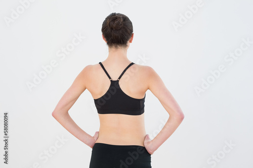 Rear view of toned woman standing against wall