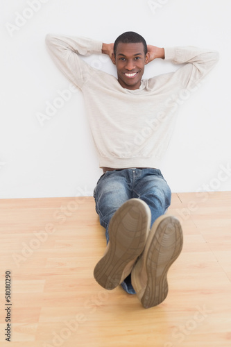 Afro young man sitting on floor in an empty room © lightwavemedia